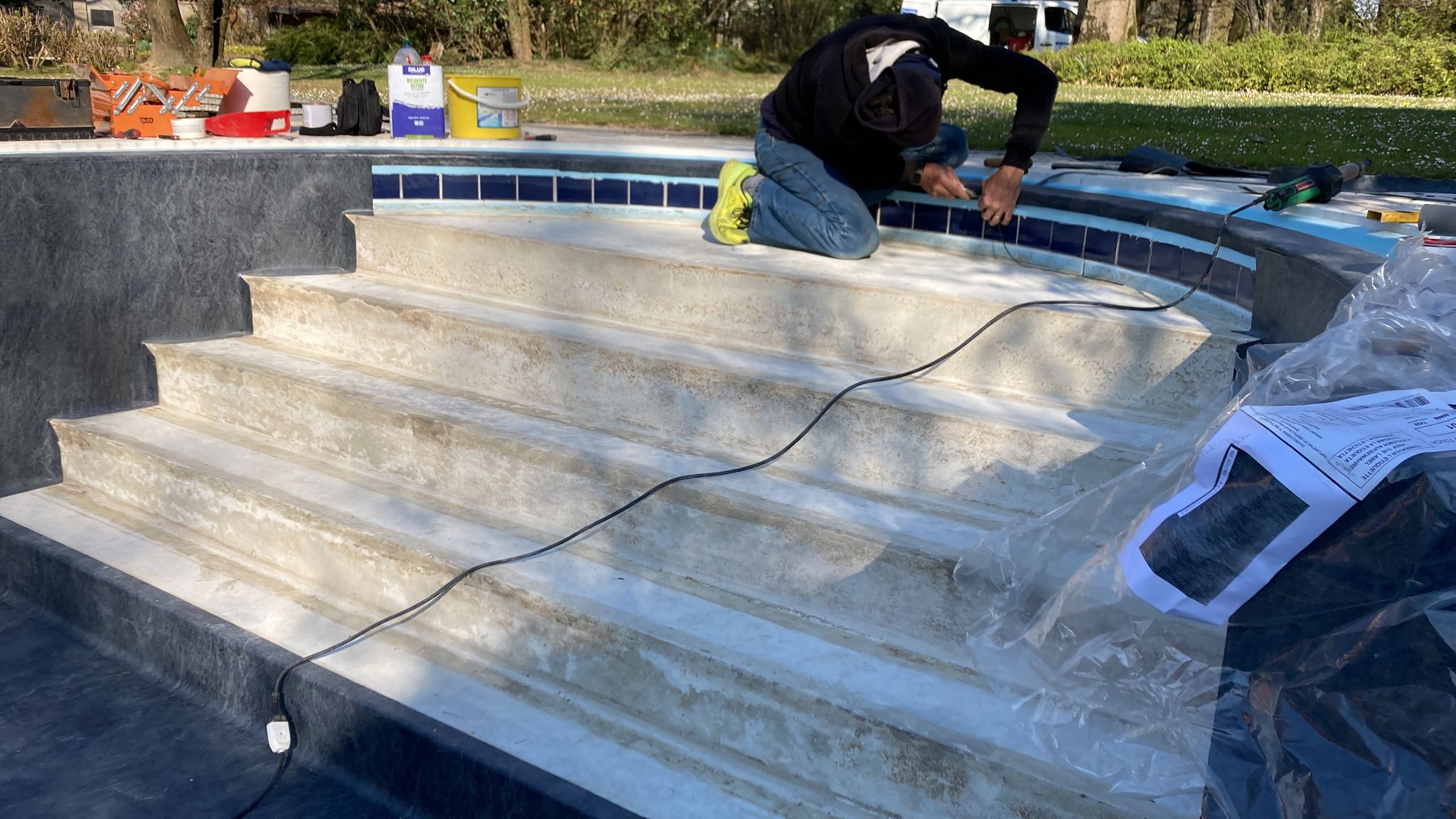 Piscina a sfioro con scala romana e cornice in mosaico, sottoposta a lavorazioni di ristrutturazione - rivestimento scala romana